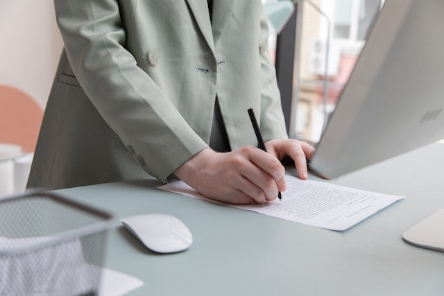 person in sage suit signing a contract
